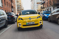 A Pop Yellow Renault 5 E-Tech electric driving through the city viewed from the front
