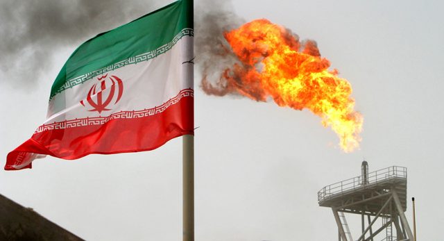 A gas flare on an oil production platform is seen alongside an Iranian flag in the Gulf