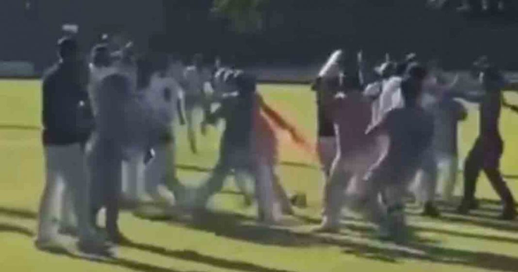 shows players hitting each other in a cricket stadium