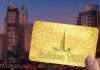 Shows a hand holding a golden card with Golden visa written on it, and UAE skyscrapers in the background