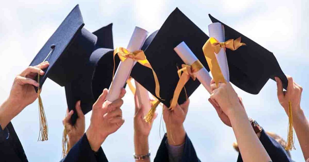 Shows many graduate students holding their degrees up