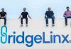 BridgeLinx Founders sitting on a roof with Bridgelinx logo on the wall