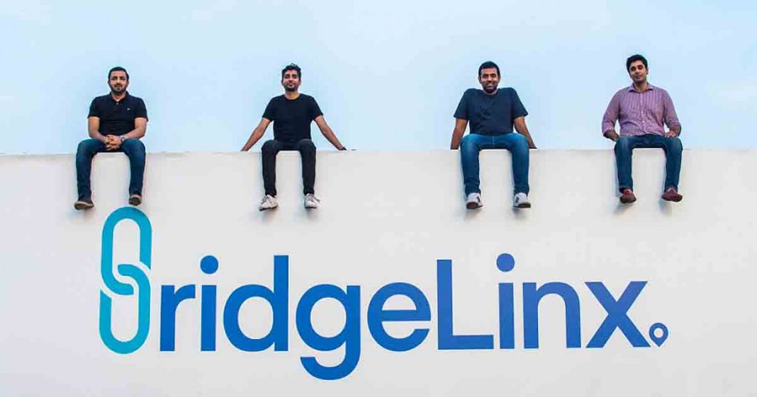 BridgeLinx Founders sitting on a roof with Bridgelinx logo on the wall